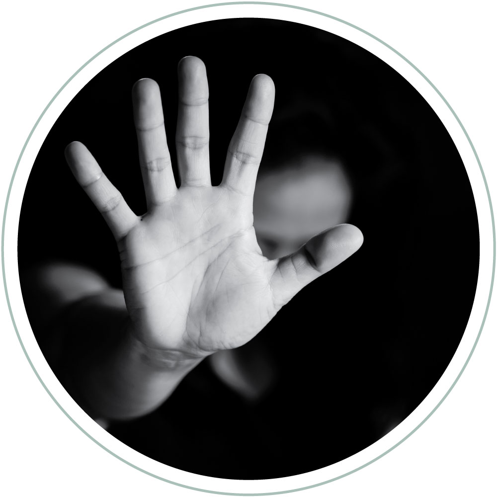 a womans hand outstretched with a blurred background. An abusive situation as the hand looks to be saying no more. Enough